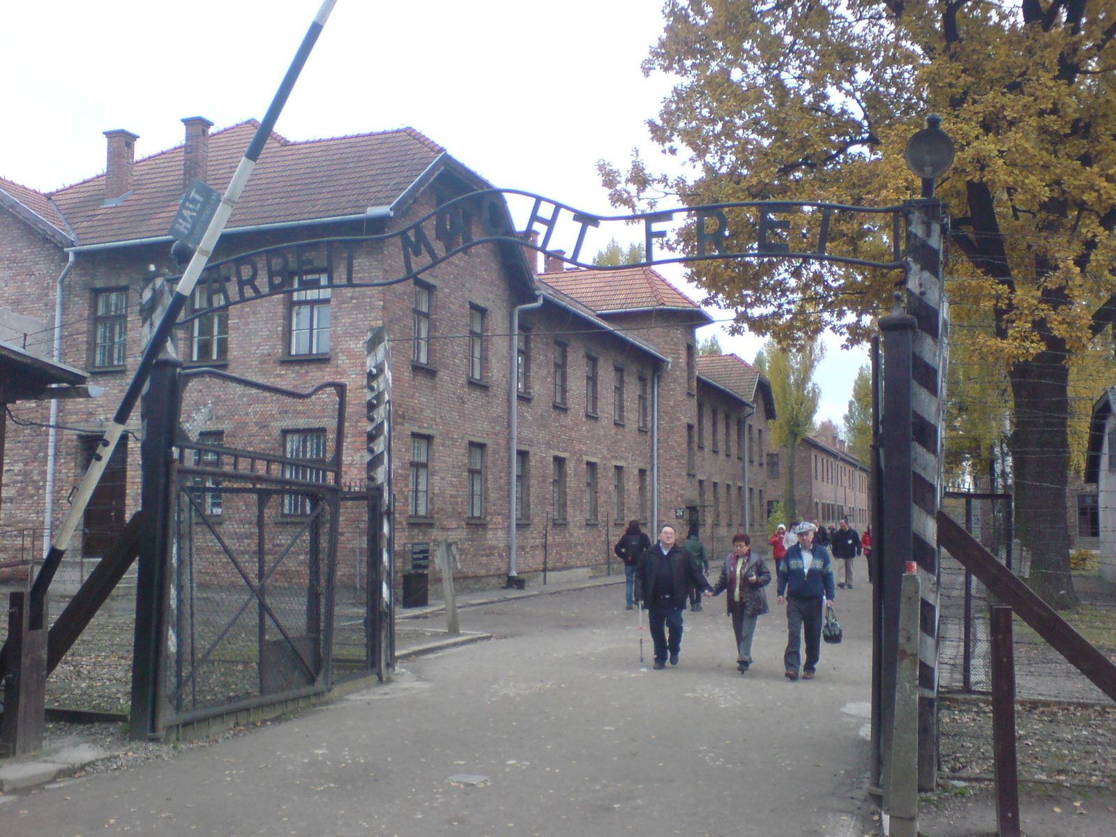 Visitors walking through the entrance gate to Auschwitz I in autumn
